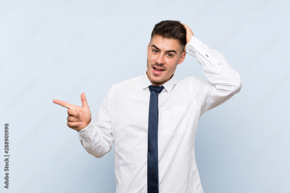 Handsome businessman over isolated blue background surprised and pointing finger to the side Handsome businessman over isolated blue background surprised and pointing finger to the side