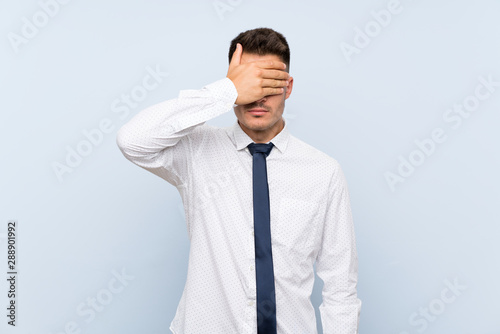 Handsome businessman over isolated blue background covering eyes by hands