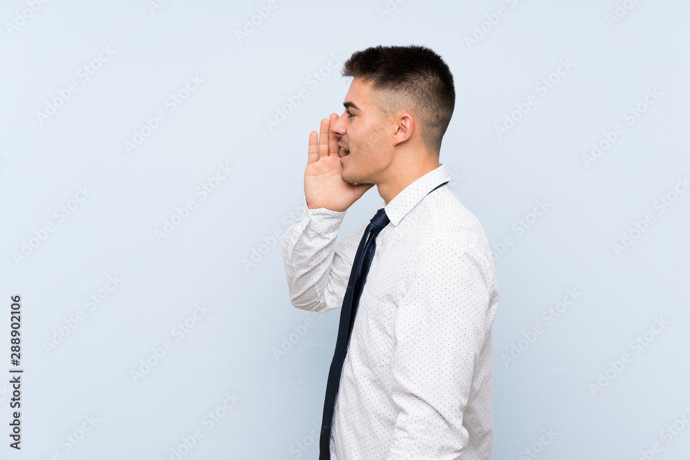 Handsome businessman over isolated blue background shouting with mouth wide open Handsome businessman over isolated blue background shouting with mouth wide open