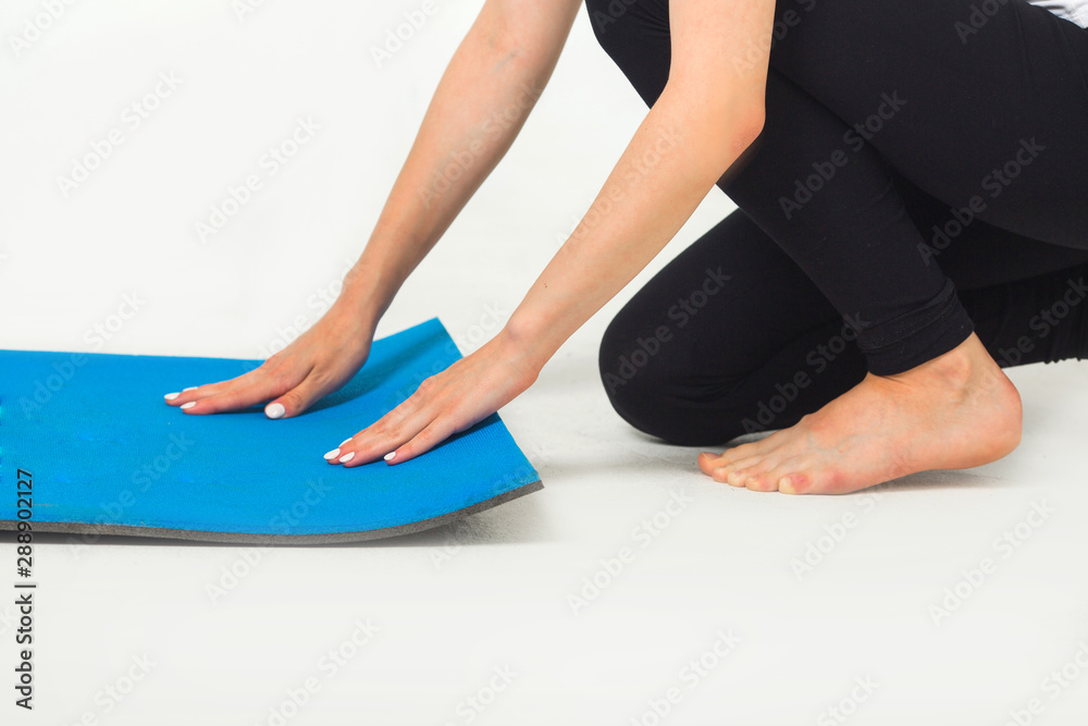 woman laying out exercise mat in studio