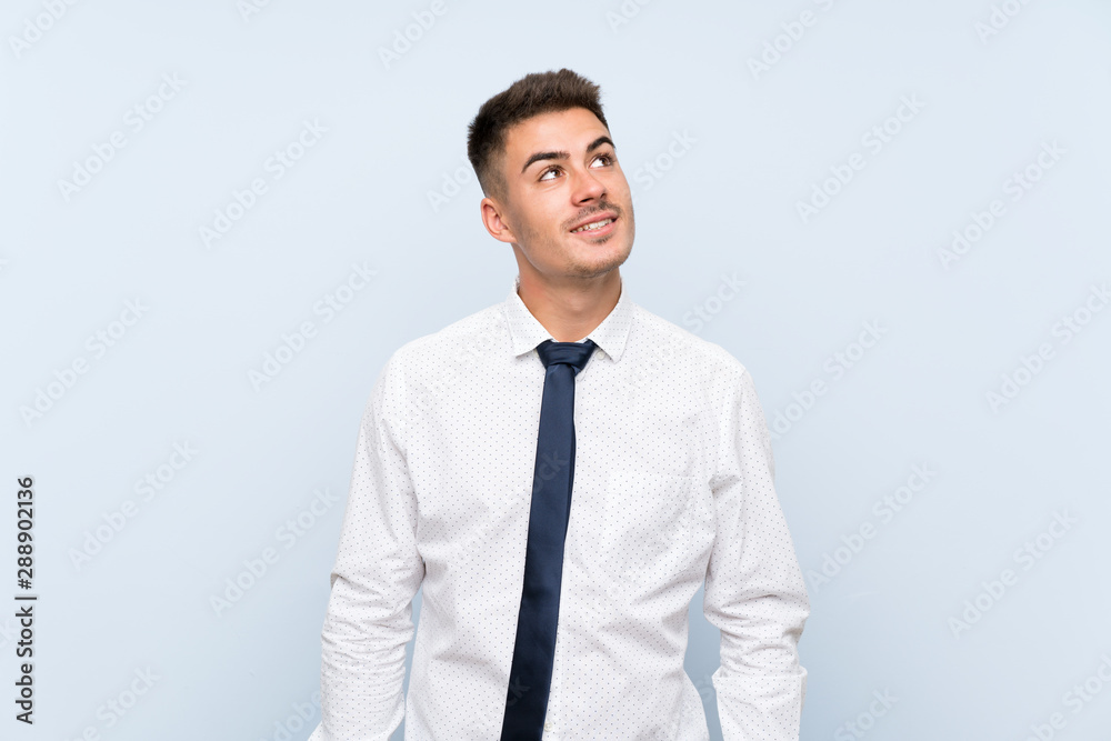 Handsome businessman over isolated blue background laughing and looking up Handsome businessman over isolated blue background laughing and looking up