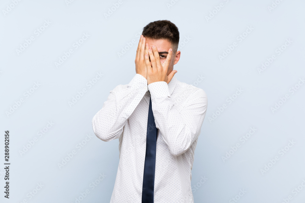 Handsome businessman over isolated blue background covering eyes and looking through fingers Handsome businessman over isolated blue background covering eyes and looking through fingers