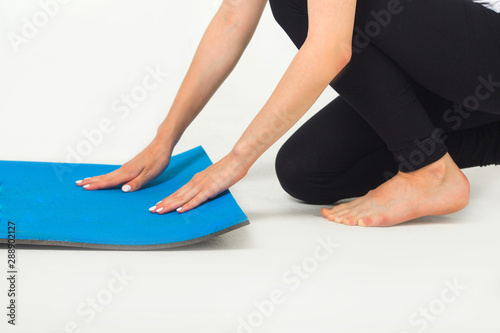 woman laying out exercise mat in studio