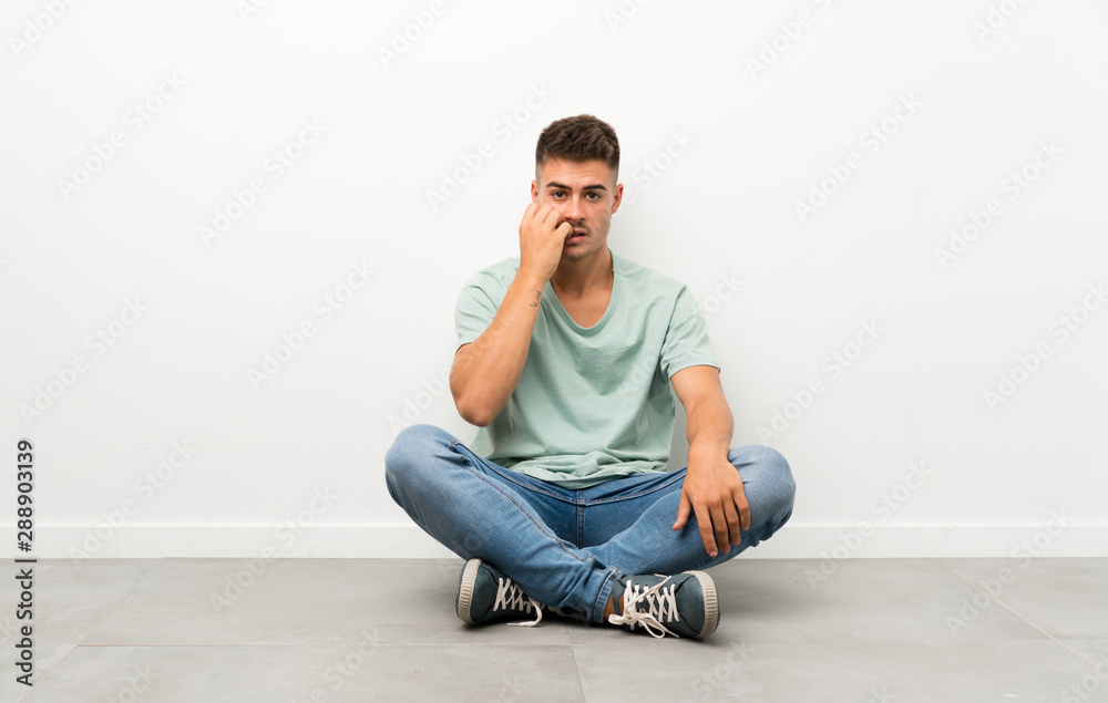 Young handsome man sitting on the floor nervous and scared Young handsome man sitting on the floor nervous and scared