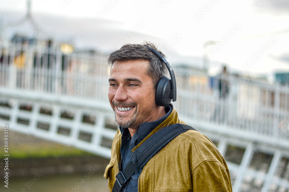 Obraz premium Spanish young man tourist in Dublin city with black headphones and leather jacket.