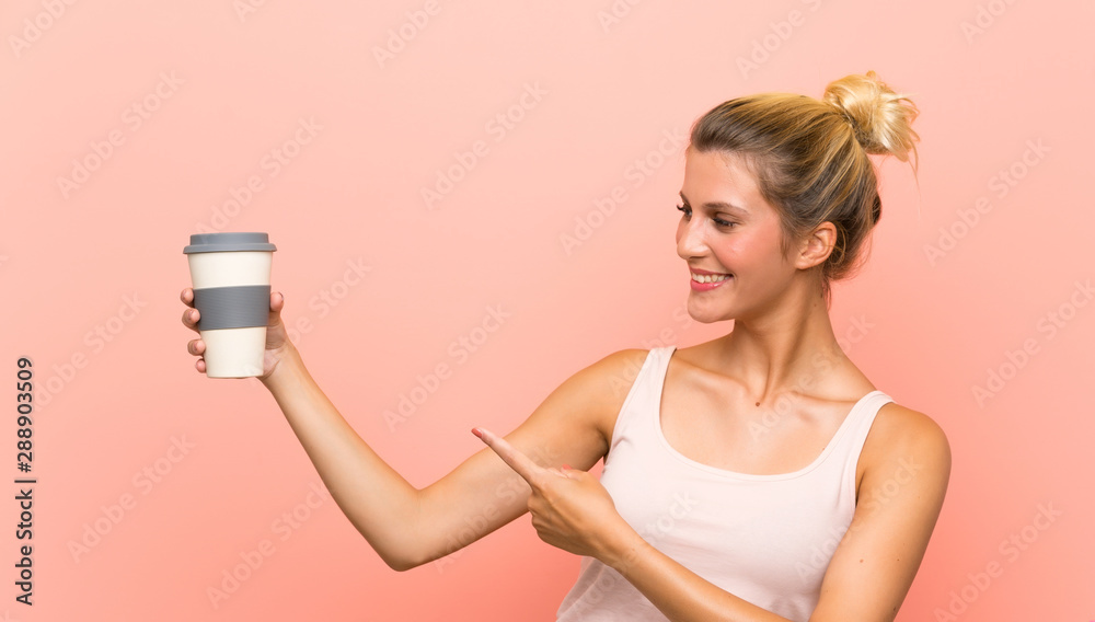 Young blonde woman holding a take away coffee and pointing it Young blonde woman holding a take away coffee and pointing it