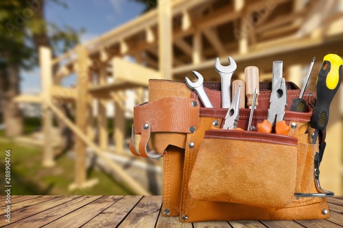 Tool belt with tools on wooden background photo