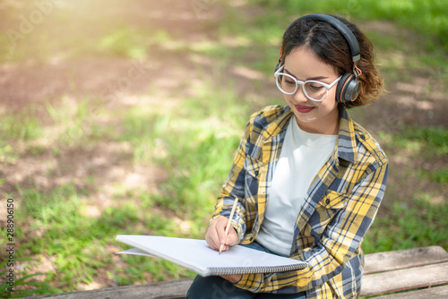 Woman listening to music and drawing on her paper, Woman wearing headphones and Writing