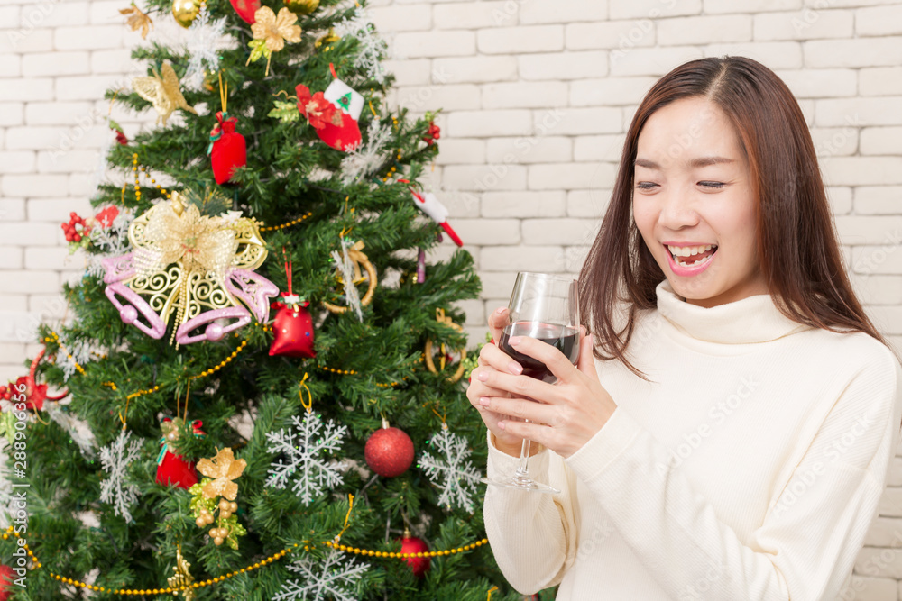 A woman with a glass of wine There is a Christmas tree in the living room. Asian female wearing are decorating Christmas trees. Merry Christmas and Happy new year. A woman with a glass of wine There is a Christmas tree in the living room. Asian female wearing are decorating Christmas trees. Merry Christmas and Happy new year.