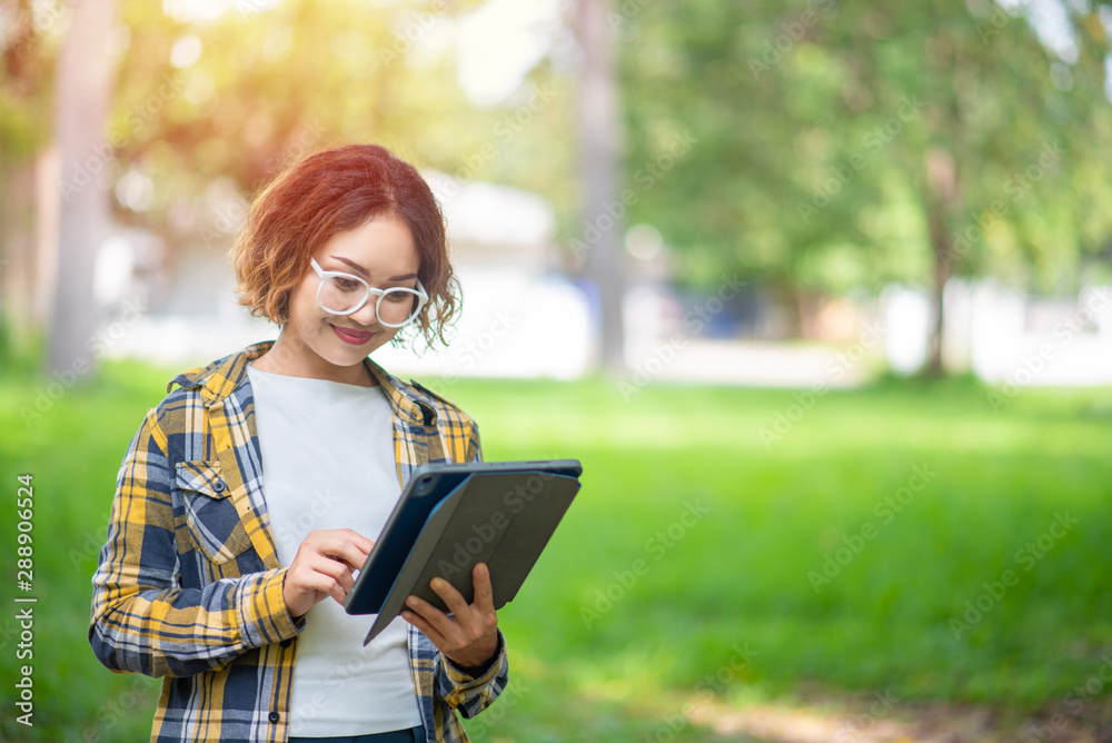 Happy woman using and looking at her digital tablet outdoors, Woman in shirt using digital tablet outdoors Happy woman using and looking at her digital tablet outdoors, Woman in shirt using digital tablet outdoors
