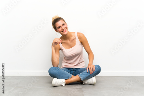 Young blonde woman sitting on the floor laughing