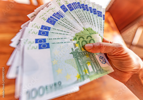 Mano femminile che tiene un mazzo di banconote da cento euro per migliaia di euro, guadagni e ricchezza facile photo