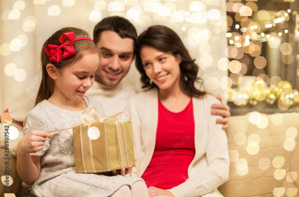 holidays, family and celebration concept - happy mother, father and little daughter with christmas present at home holidays, family and celebration concept - happy mother, father and little daughter with christmas present at home