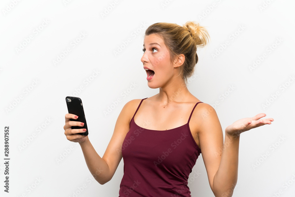 Young blonde woman using mobile phone with surprise facial expression Young blonde woman using mobile phone with surprise facial expression
