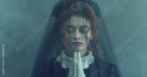 A red-haired woman in a black vintage dress, looking like a dead bride. Halloween. Horrors.
