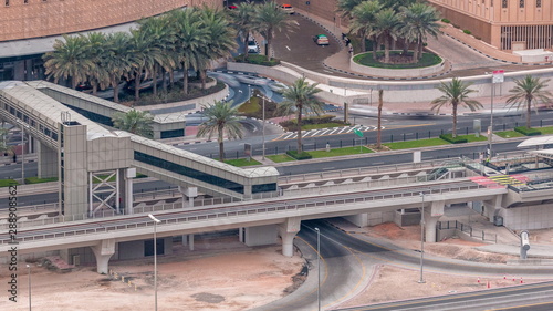Aerial top view of traffic near mall with footbridge from tram stop timelapse in Dubai Marina in Dubai, UAE.