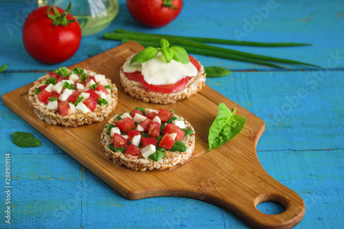 healthy sandwiches rice  cakes with diced tomatoes cheese spinach basil   on cutting board 