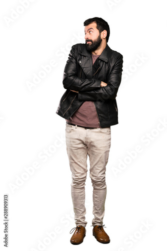 Handsome man with beard making doubts gesture while lifting the shoulders over isolated white background