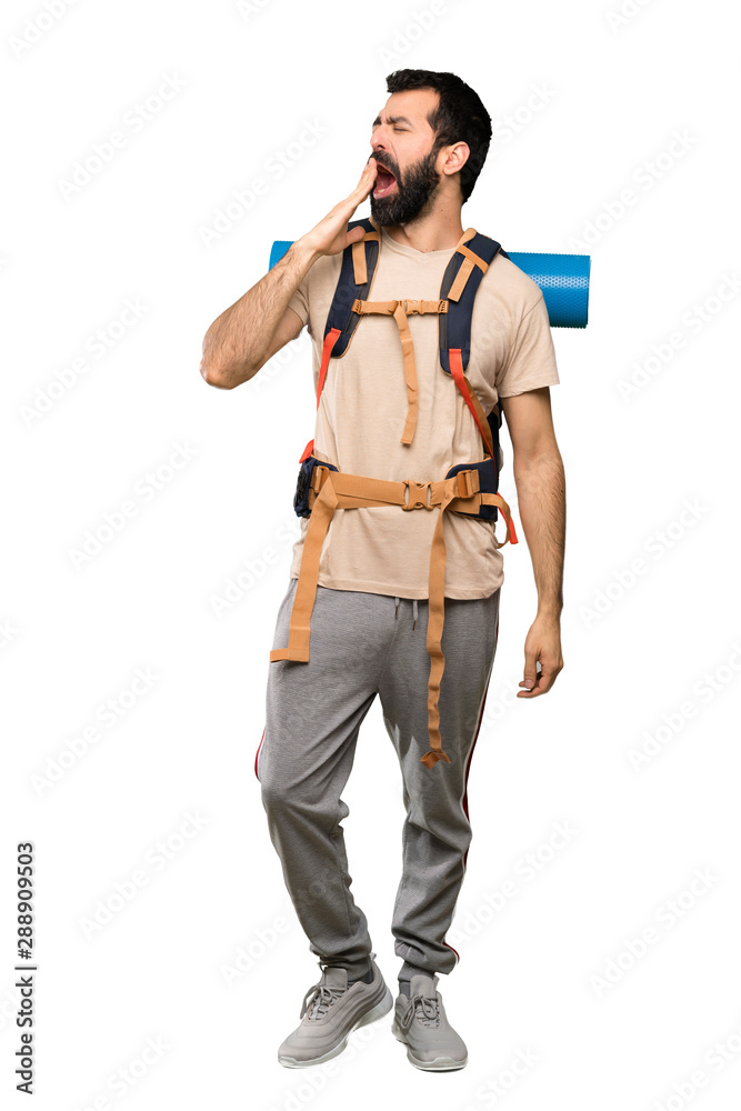 Hiker man yawning and covering wide open mouth with hand over isolated white background Hiker man yawning and covering wide open mouth with hand over isolated white background
