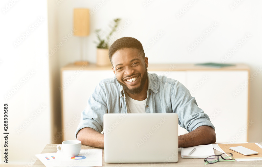 Positive black freelancer posing to camera and laughing