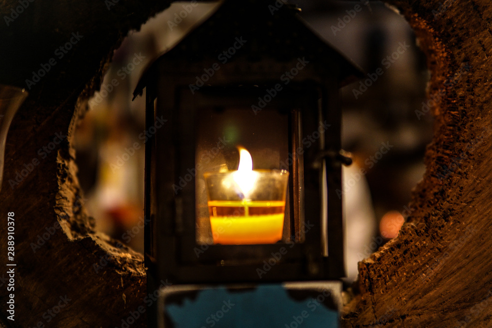 Light in a candle cup in a small wooden house