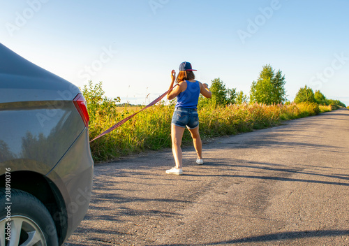 Beautiful girl trying to push broken car to repair shop.