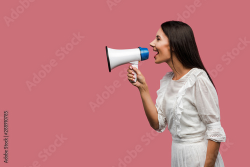 side view of woman screaming in megaphone isolated on pink