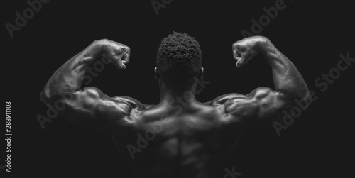 African athlete demonstrating double biceps pose over black studio background © Prostock-studio