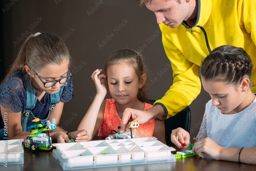 Obraz premium Kids creating robots with teacher. Early development, diy, innovation, modern technology concept.