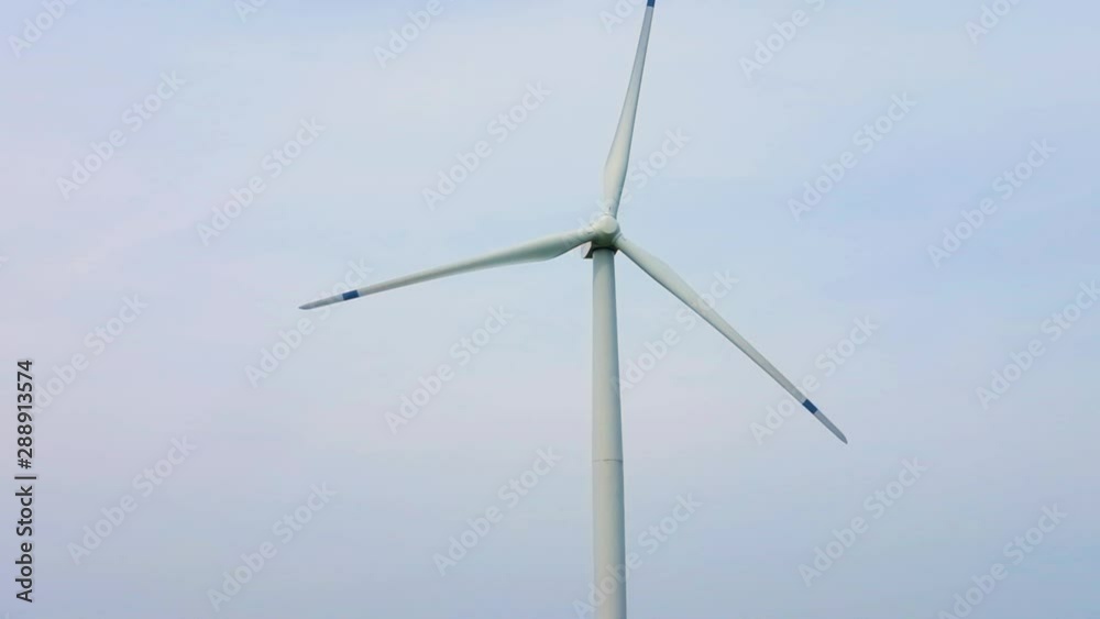 rotating blades of a windmill propeller on blue sky background. Wind power generation. Pure green energy. rotating blades of a windmill propeller on blue sky background. Wind power generation. Pure green energy.