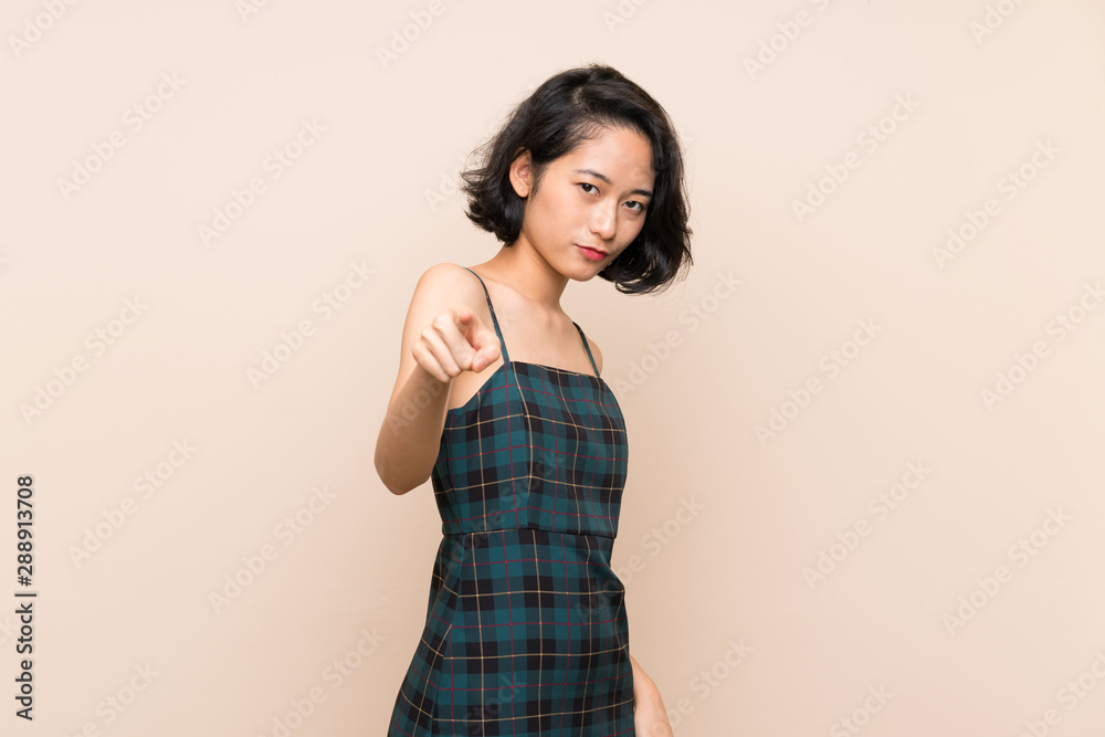 Asian young woman over isolated yellow wall points finger at you with a confident expression Asian young woman over isolated yellow wall points finger at you with a confident expression