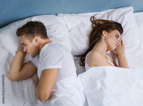 Portrait of unhappy young couple on the bed in bedroom. Love crisis, relationship, frustrated concept picture. photo