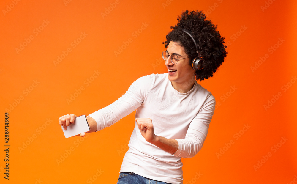 Active carefree black guy in wireless headphones enjoying music Active carefree black guy in wireless headphones enjoying music