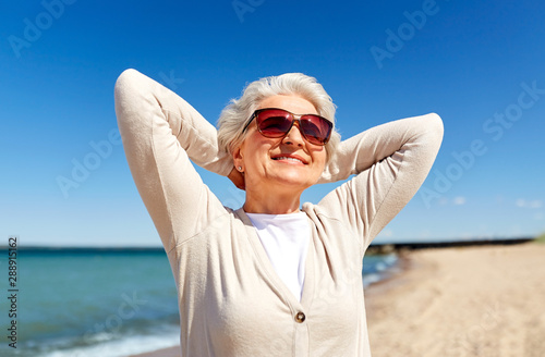 people and leisure concept - portrait of happy senior woman in sunglasses on beach in estonia © Syda Productions