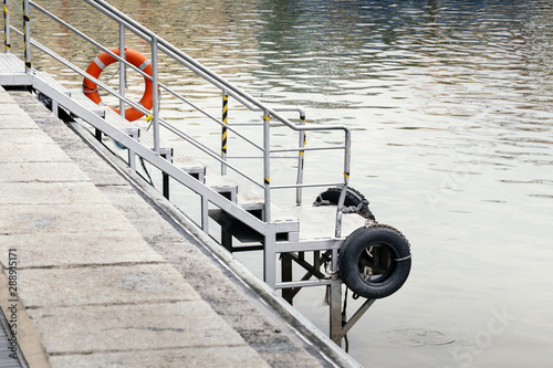 iron stair or step by the water, descent to the water. little pier by lake or canal with cushion and lifebouy for safety © happycreator