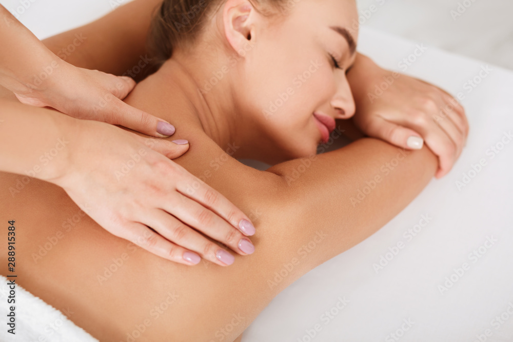 Millennial woman receiving shoulder massage in the spa Millennial woman receiving shoulder massage in the spa