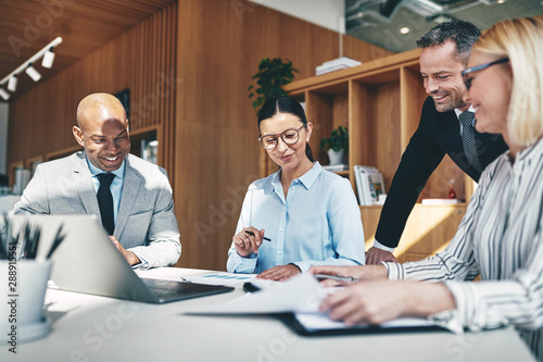 Laughing businesspeople going over paperwork together during an office meeeting photo