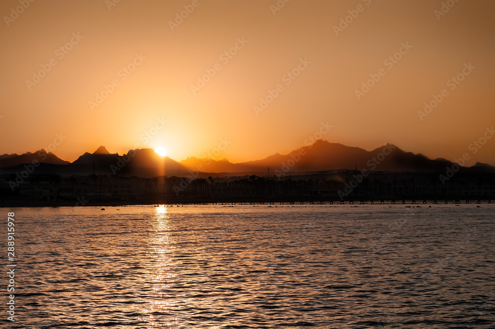 sunset landscape sea and mountain above orange sky