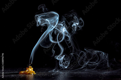 Smoke on a dying candle against a dark background.