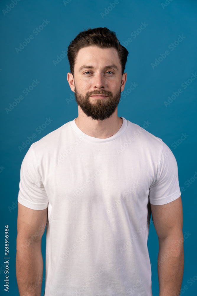 Young man wearing white blank t-shirt and blue background, standing on the street. Portrait of a handsome man. Young man wearing white blank t-shirt and blue background, standing on the street. Portrait of a handsome man.