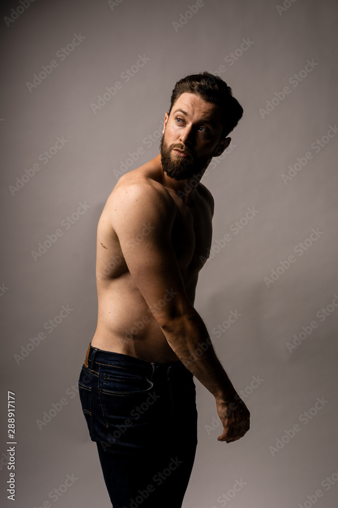 Technical staff. Smart handsome man with a beard is in search of something. Topless model.