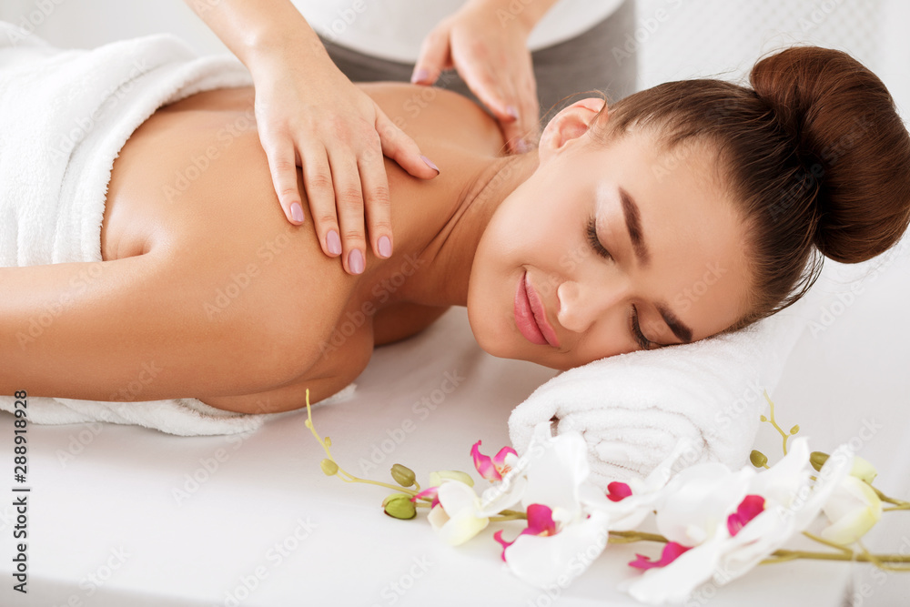 Woman enjoying shoulder massage, relaxing with closed eyes Woman enjoying shoulder massage, relaxing with closed eyes