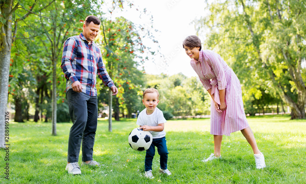 family, leisure and people concept - happy mother, father and little son with ball playing soccer at summer park family, leisure and people concept - happy mother, father and little son with ball playing soccer at summer park