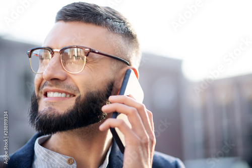 Handsome man smiling while speaking with girlfriend by phone