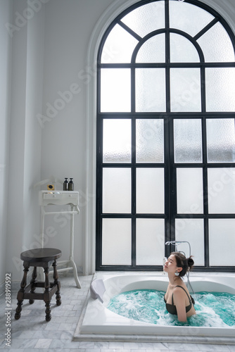 Beautiful women wearing green bikini in the jacuzzi with high transparent glass window in natural light scene / therapy concept /wellness lifestyle / beautiful asian women