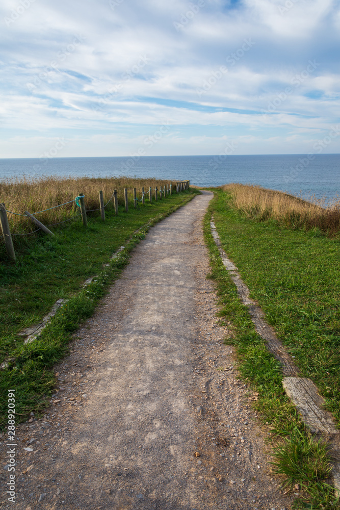 Lonely green road to walk on the coast at sunset in Comillas, Cantabria, Spain Lonely green road to walk on the coast at sunset in Comillas, Cantabria, Spain