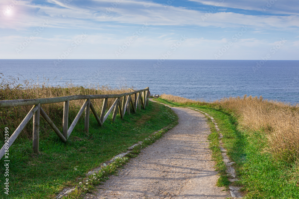 Landscape with fenced path for walking on the coast at sunset in Comillas, Cantabria, Spain