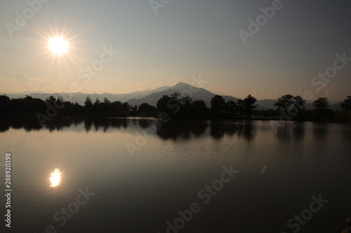 Tramonto sul lago con il sole nel cielo che si riflette sulla acqua