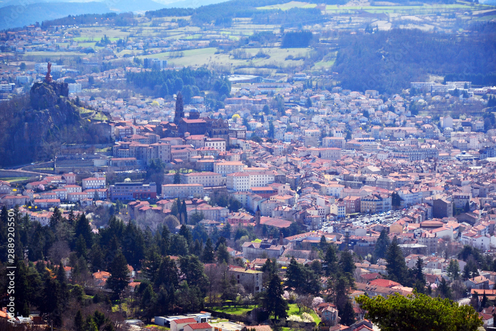Aiguilhe, France - March 30th 2019 : view of the city Le Puy-en-Velay, built in a volcanic landscape. You can see the statue of the Virgin, the Church Saint Michel d'Aiguilhe and the cathedral.