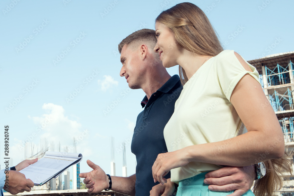 portrait of nice young couple studying contract on construction area background portrait of nice young couple studying contract on construction area background
